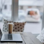Ordinateur portable et café sur une table cosy – travailler depuis chez soi dans un cadre inspirant