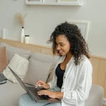 Femme travaillant sur son ordinateur depuis chez elle pour créer un business en ligne avec peu de moyens