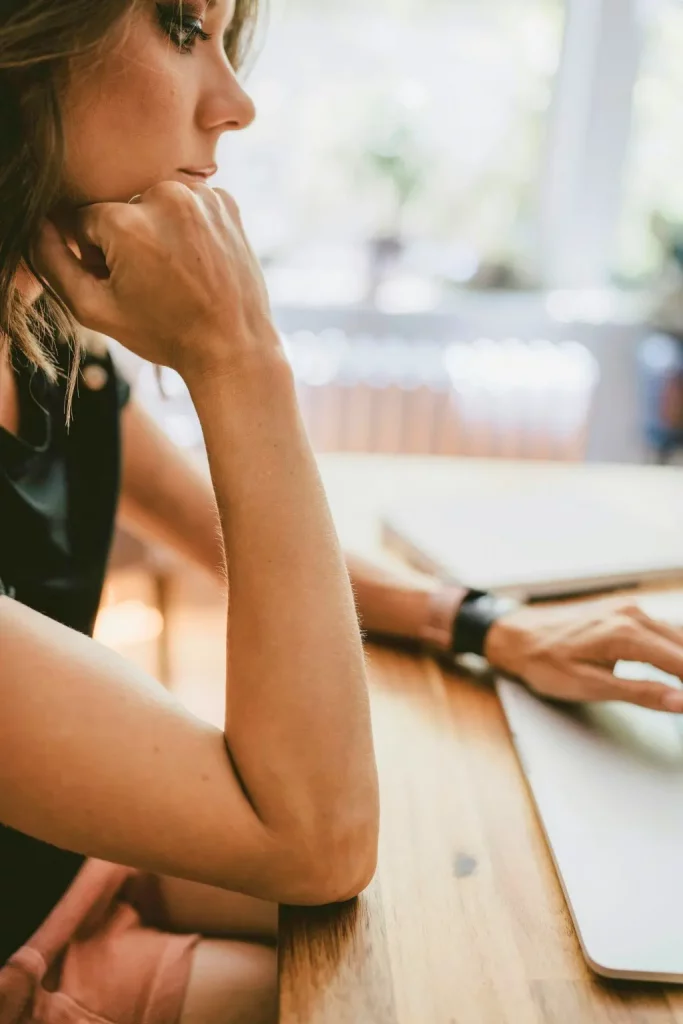 femme réfléchissant à travailler en ligne depuis chez soi sur ordinateur portable